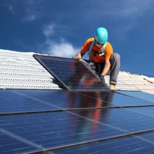 Solar installer on roof Solar installer installing solar panels on residential building